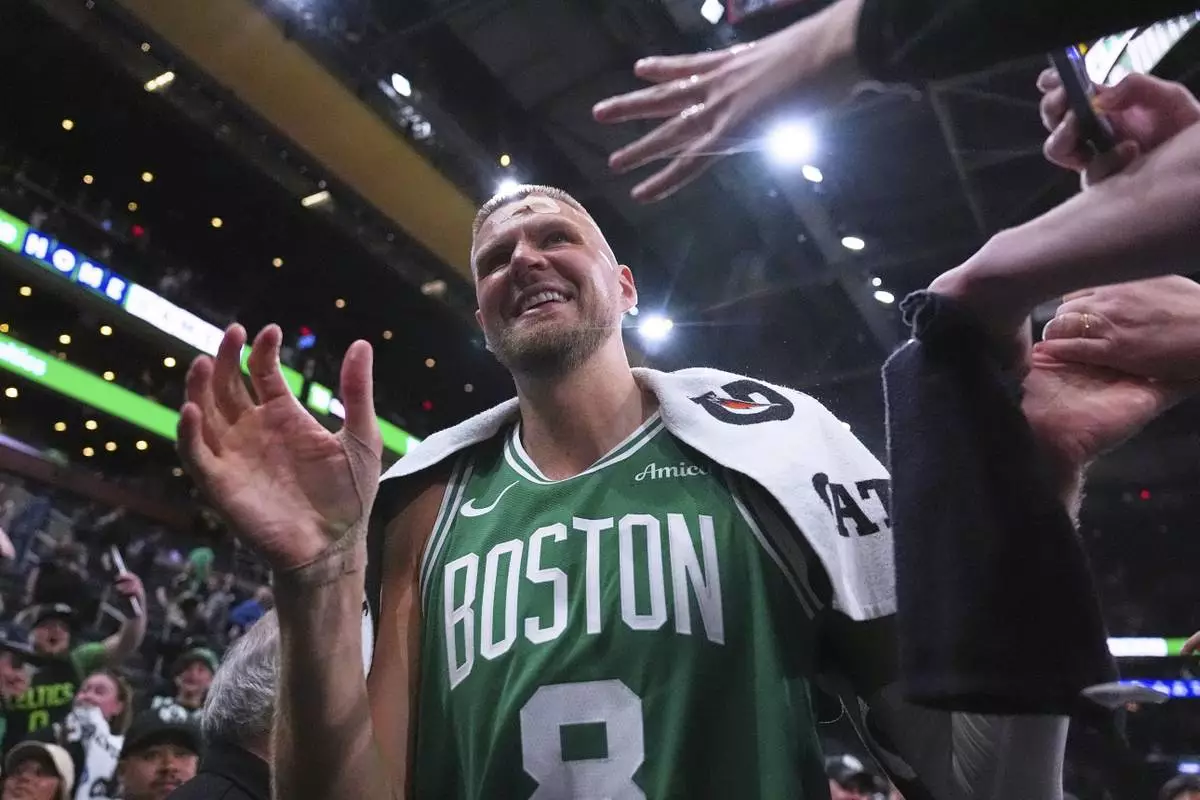 With his head bandaged after an injury, Boston Celtics center Kristaps Porzingis (8) is congratulated by fans after defeating the Orlando Magic in game 2 of a first-round NBA playoff basketball series, Wednesday, April 23, 2025, in Boston. (AP Photo/Charles Krupa)