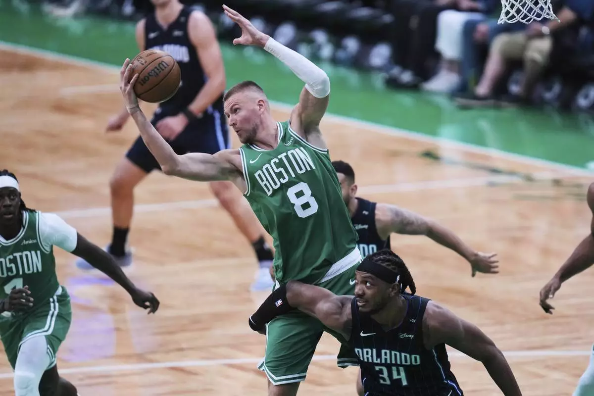 Boston Celtics center Kristaps Porzingis (8) grabs a rebound against Orlando Magic center Wendell Carter Jr. (34) during the second half in game 2 of a first-round NBA playoff basketball series, Wednesday, April 23, 2025, in Boston. (AP Photo/Charles Krupa)