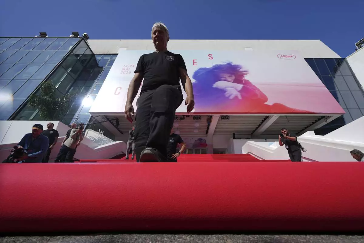 Crew members install the red carpet at the Palais des Festivals ahead of the opening ceremony of the 78th international film festival, Cannes, southern France, Tuesday, May 13, 2025. (AP Photo/Natacha Pisarenko)