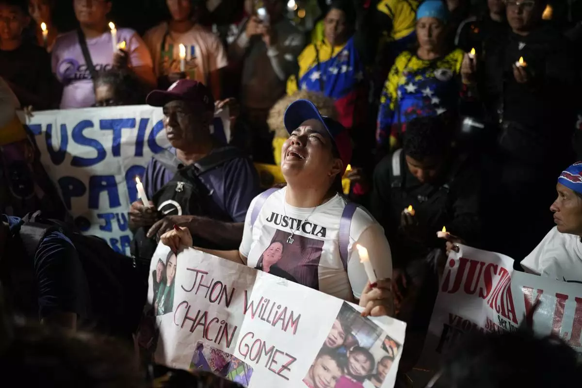 People with photos of their relatives who were deported from the U.S. to a prison in El Salvador, for being alleged members of the Tren de Aragua gang, cry and pray outside El Salvador's embassy in Caracas, Venezuela, April 2, 2025. (AP Photo/Ariana Cubillos)