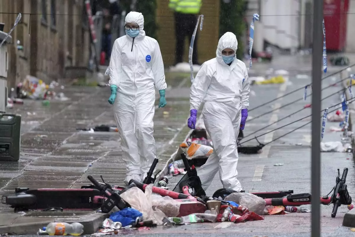 Forensic officers examine the site where a 53-year-old British man plowed a minivan into a crowd of Liverpool soccer fans who were celebrating the city's Premier League championship Monday, injuring more than 45 people in Liverpool, England, Tuesday, May 27, 2025. (AP Photo/Jon Super)