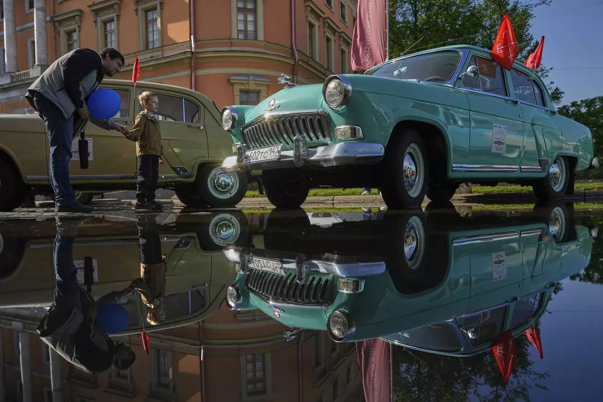 A man and a child examine a Soviet era GAZ M21 Volga car at a transport festival in St. Petersburg, Russia, Saturday, May 24, 2025. (AP Photo/Dmitri Lovetsky)