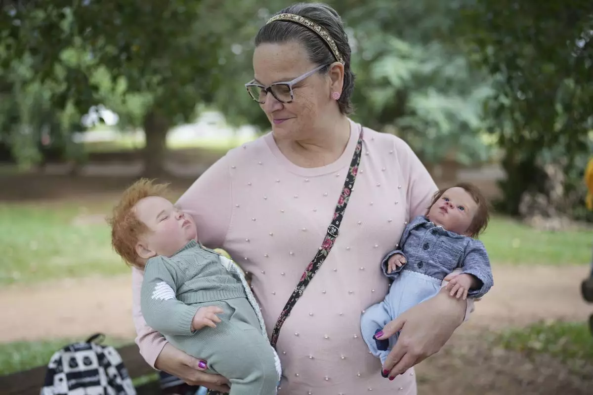 Ana Paula Vilela holds her dolls during a group gathering to bond and show off their hyper-realistic reborn baby dolls, in a park in Sao Paulo, Saturday, May 24, 2025. (AP Photo/Andre Penner)