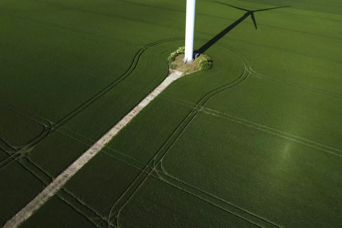 The shadow of a wind turbine falls on a field at a wind farm near Aschersleben, Germany, Monday, May 26, 2025. (AP Photo/Matthias Schrader)