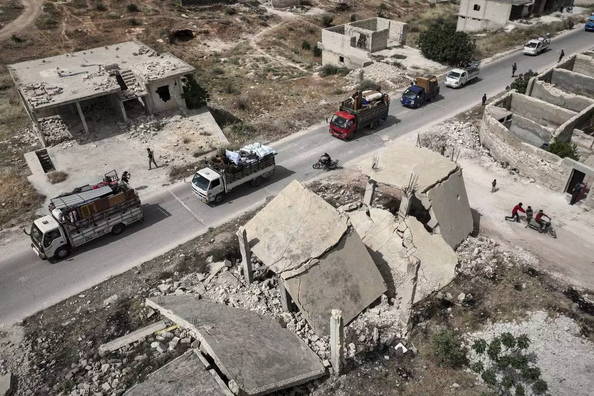 Trucks and vans carrying around 60 displaced families arrive in their village after more than five years in the Atmeh camps near the Syrian-Turkish border, in Kafr Sijna, south of Idlib, Syria, Sunday, May 18, 2025. (AP Photo/Ghaith Alsayed)