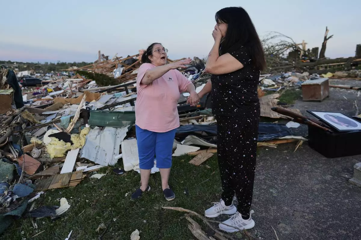 Bea Johnson, left, reaches for her sister Kristie Sexton, right, as she reacts standing next to her destroyed home after a severe storm passed through the area, Saturday, May 17, 2025, in London, Ky. (AP Photo/Carolyn Kaster)
