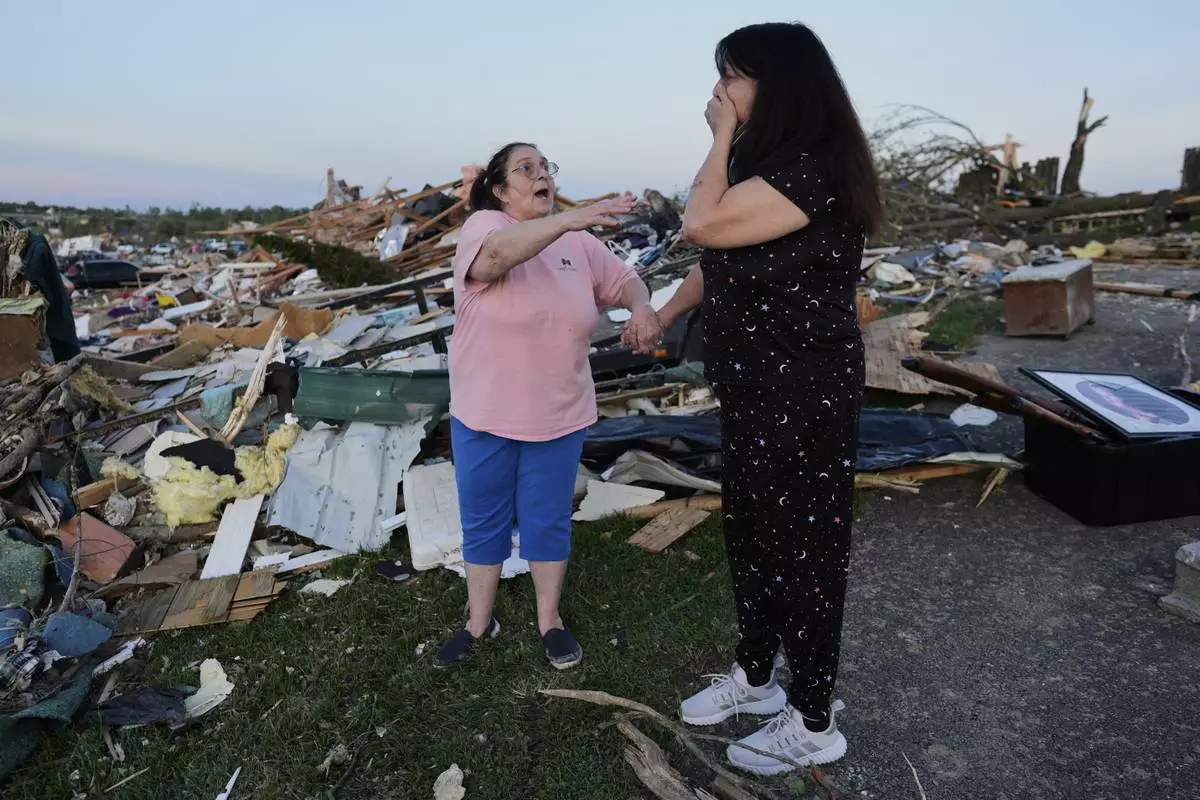 Bea Johnson, left, reaches for her sister Kristie Sexton, right, as she reacts standing next to her destroyed home after a severe storm passed through the area, Saturday, May 17, 2025, in London, Ky. (AP Photo/Carolyn Kaster)
