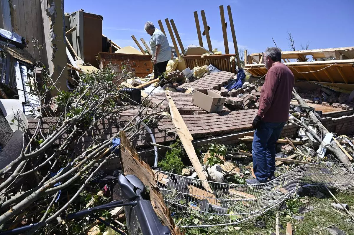 Doris Hensley, center, and Don Allen look over the remains of her home following severe weather in London, Ky., Saturday, May 17, 2025. (AP Photo/Timothy D. Easley)