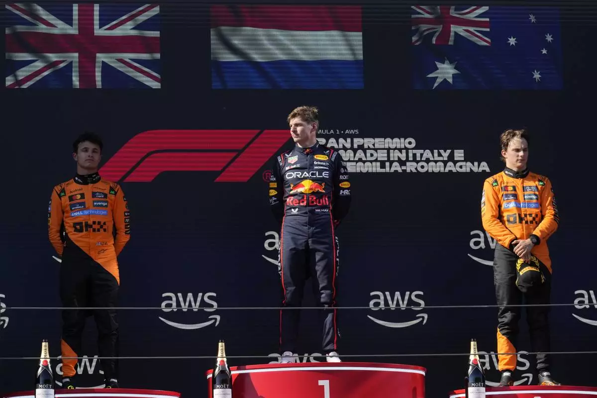 Red Bull driver Max Verstappen of the Netherlands celebrates on the podium after winning the Italian Emilia Romagna Formula One Grand Prix, flanked with McLaren driver Lando Norris of Britain, left, and McLaren driver Oscar Piastri of Australia, at the Enzo and Dino Ferrari racetrack in Imola, Italy, Sunday, May 18, 2025. (AP Photo/Luca Bruno)