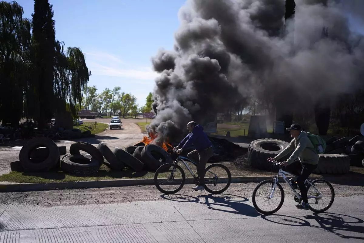 Tires burn outside the "Cerro Negro" ceramics factory after company lay offs in Olavarria, Argentina, Monday, April 28, 2025. (AP Photo/Victor R. Caivano)
