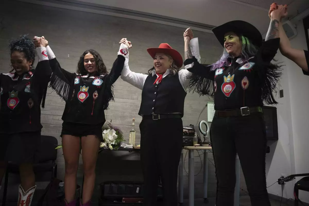 Mexican singer Vivir Quintana, center, and band members join hands before the introduction of her new album "Cosas que Sorprenden a la Audiencia" or Things that Surprise the Audience, in Mexico City, Thursday, April 24, 2025. Quintana's first "corridos" album tells the stories of women who were incarcerated for killing their abusers while defending themselves. (AP Photo/Aurea Del Rosario)