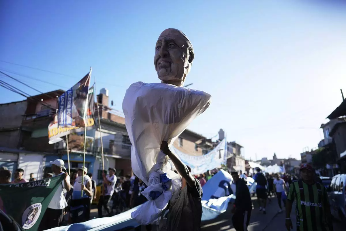 A mourner holds a giant puppet depicting the late Pope Francis during a caravan through emblematic places of his life in Buenos Aires, Argentina, Saturday, April 26, 2025, on the day of his funeral in Rome. (AP Photo/Natacha Pisarenko)