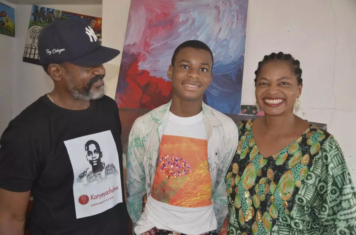 Kanyeyachukwu Tagbo Okeke, a 15 year-old autistic Nigerian, who set a Guinness World Record for the world's largest art canvas, is photograph with his parents in Abuja, Nigeria, Friday, April 18, 2025. (AP Photo/Olamikan Gbemiga)