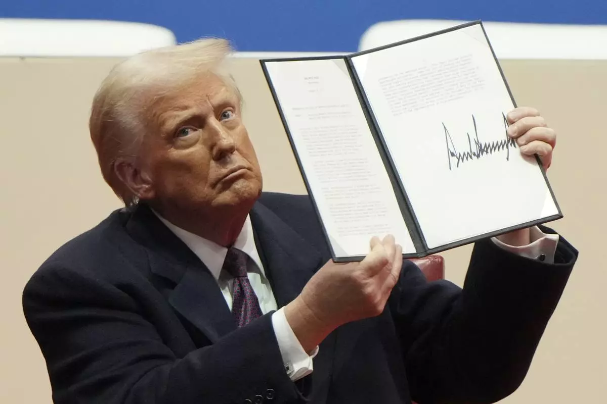 FILE - President Donald Trump holds up an executive order after signing it at an indoor Presidential Inauguration parade event in Washington, Jan. 20, 2025. (AP Photo/Matt Rourke, File)