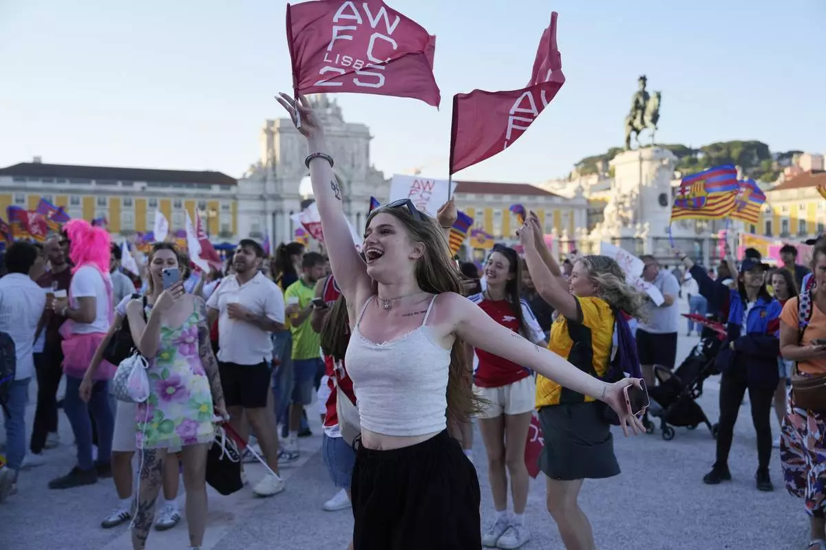 An Arsenal fan waves a flag at Lisbon's riverside Comercio square, on the eve of the women's Champions League final soccer match between Arsenal and FC Barcelona in Lisbon, Friday, May 23, 2025. (AP Photo/Ana Brigida)