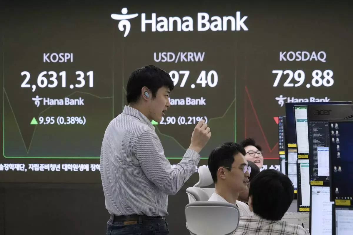 Currency traders work near a screen showing the Korea Composite Stock Price Index (KOSPI), top left, and the foreign exchange rate between U.S. dollar and South Korean won, top center, at the foreign exchange dealing room of the KEB Hana Bank headquarters in Seoul, South Korea, Friday, May 16, 2025. (AP Photo/Ahn Young-joon)