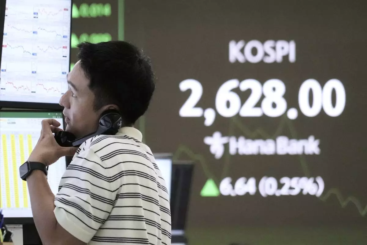 A currency trader talks on the phone near a screen showing the Korea Composite Stock Price Index (KOSPI) at the foreign exchange dealing room of the KEB Hana Bank headquarters in Seoul, South Korea, Friday, May 16, 2025. (AP Photo/Ahn Young-joon)