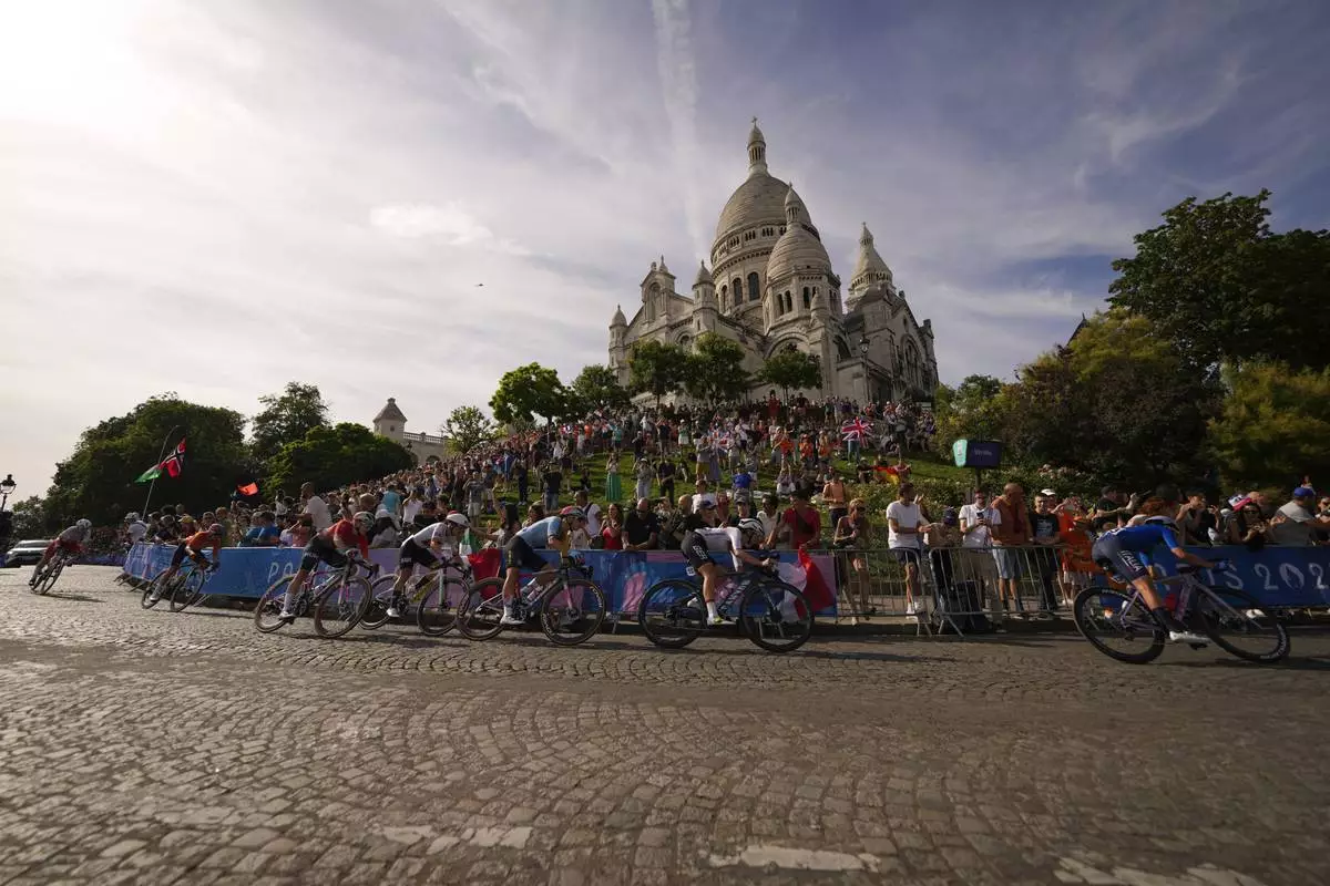 FILE - Competitors ride past the Sacre Coeur basilica, during the women's road cycling event, at the 2024 Summer Olympics, Sunday, Aug. 4, 2024, in Paris, France. (AP Photo/Vadim Ghirda, File)