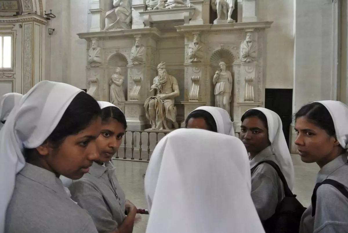 FILE - Nuns talk in front of Italian Renaissance artist Michelangelo Buonarroti's Moses statue, part of a funerary monument he designed for Pope Julius II inside San Pietro in Vincoli Basilica in Rome, July 2, 2013. (AP Photo/Gregorio Borgia, File)