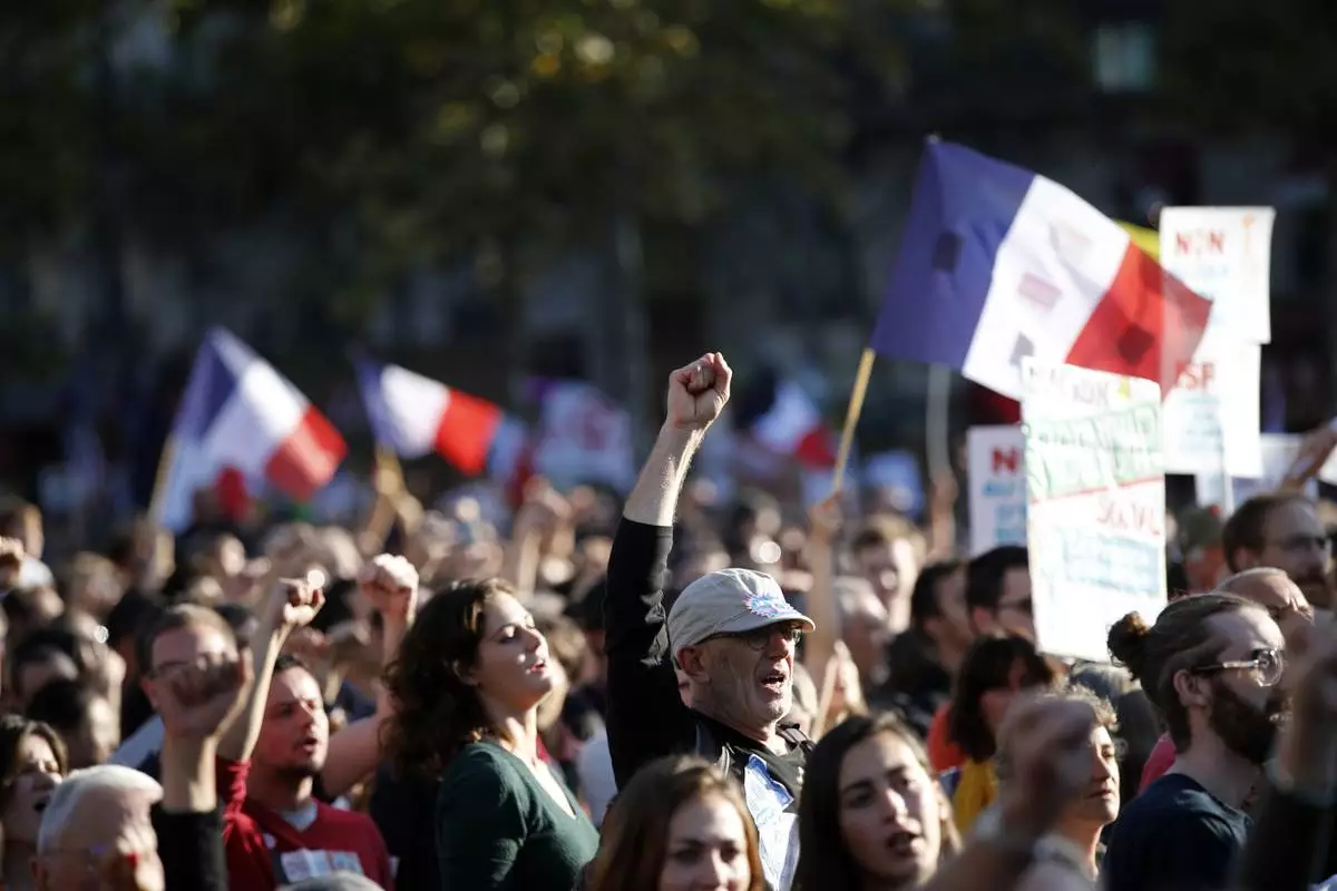 FILE - A supporter of French far-left leader Jean-Luc Melenchon raises his fist as his leader delivers his speech during a protest over the president's labor reform in Paris, France, Sept. 23, 2017. (AP Photo/Christophe Ena, File)