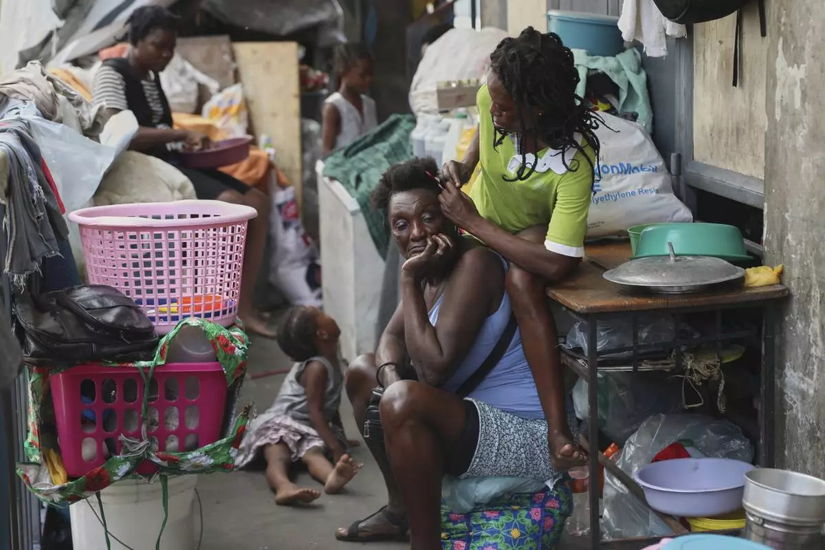 A woman combs the hair of another at a shelter for families displaced by gang violence, in Port-au-Prince, Haiti, Thursday, May 22, 2025. (AP Photo/Odelyn Joseph)