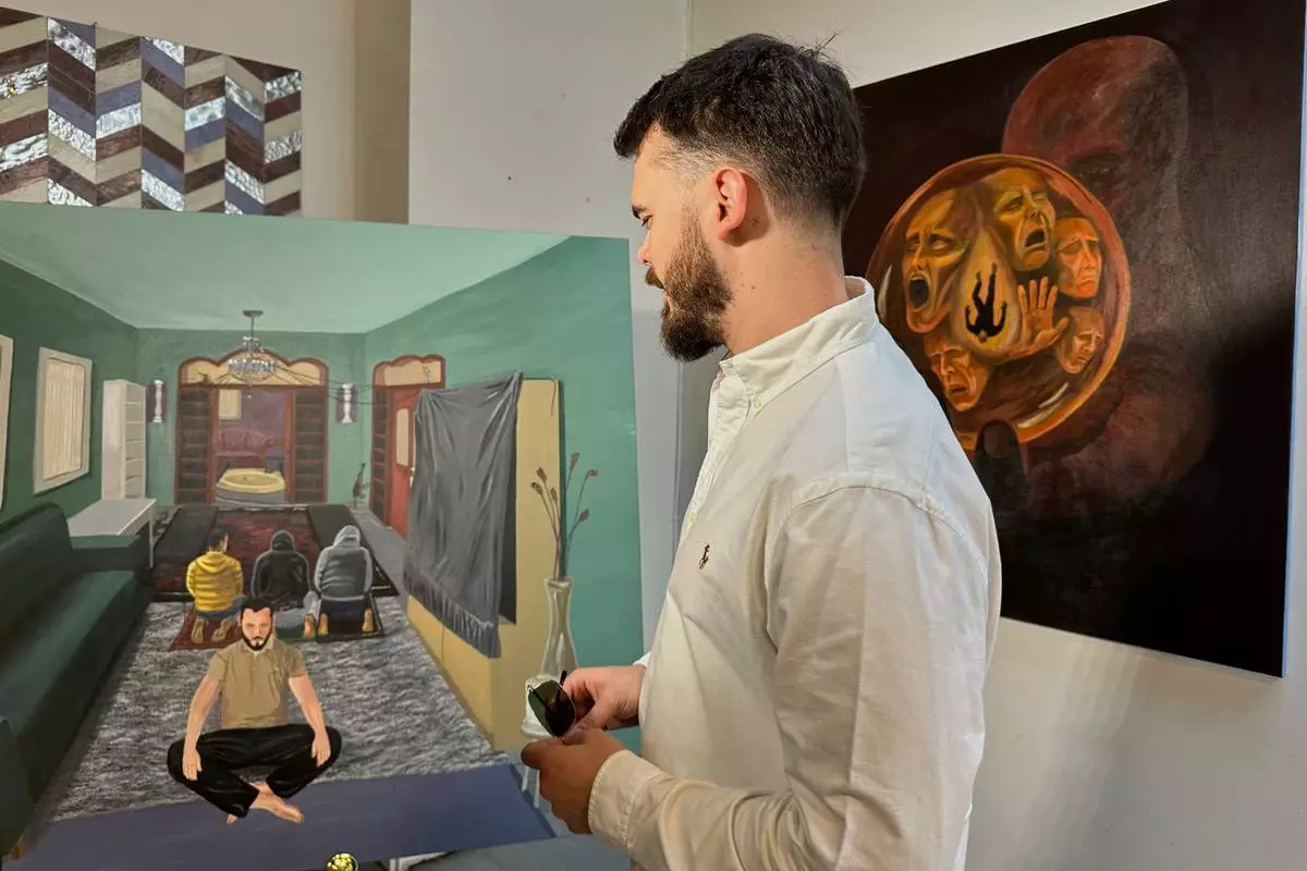 Andrei Kozlov, who was taken hostage by Hamas during the Oct. 7, 2023, attack on Israel, looks at his painting, “One God,” on Monday, May 19, 2025, at his studio in New York. (AP Photo/Matt Sedensky)