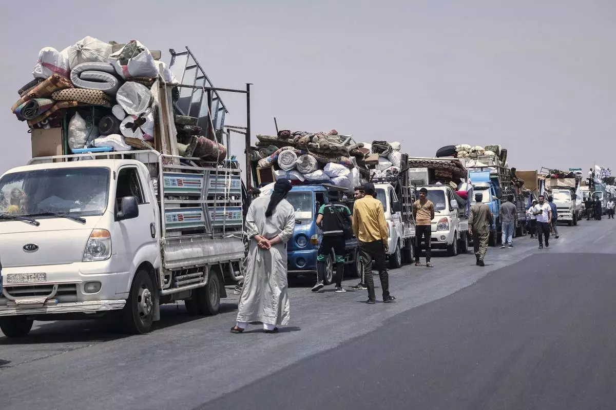 Trucks carrying around 60 displaced families gather on the highway as they head to their village, Kafr Sijna, after more than five years in the Atmeh camps near the Syrian-Turkish border, on a highway north of Kafr Sijna, Syria, Sunday, May 18, 2025. (AP Photo/Ghaith Alsayed)