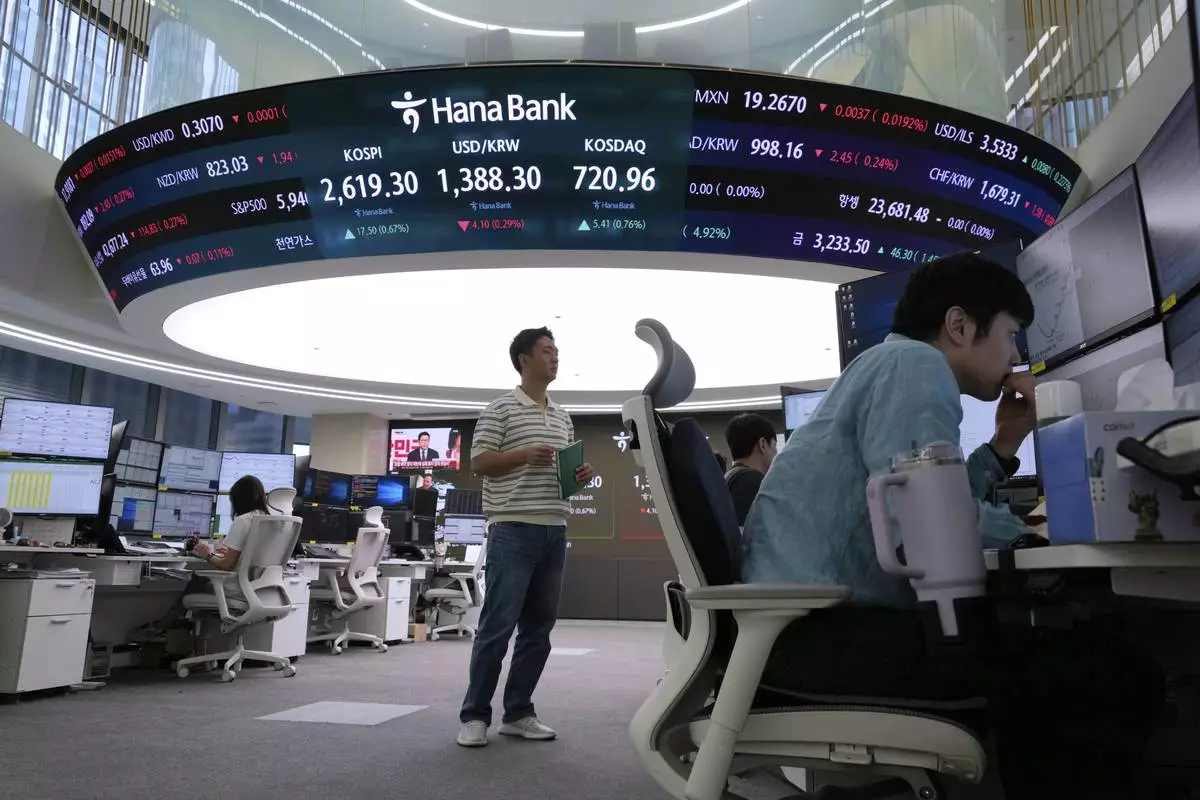 Currency traders work near a screen showing the Korea Composite Stock Price Index (KOSPI), top center left, and the foreign exchange rate between U.S. dollar and South Korean won, top center, at the foreign exchange dealing room of the KEB Hana Bank headquarters in Seoul, South Korea, Wednesday, May 21, 2025. (AP Photo/Ahn Young-joon)