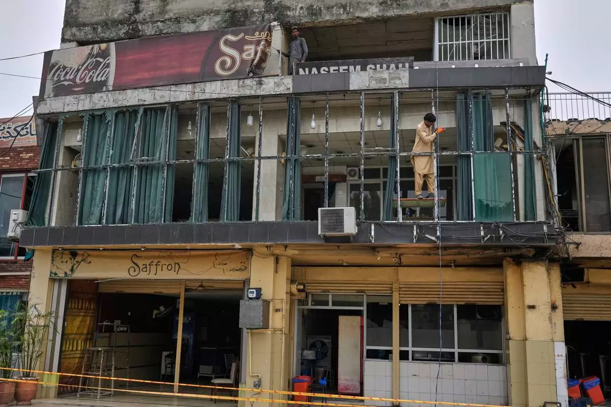 Workers repair broken glass of a building at the parking area of Rawalpindi Cricket Stadium, where a suspected Indian drone was crashed on Thursday, in Rawalpindi, Pakistan, Friday, May 9, 2025. (AP Photo/Anjum Naveed)