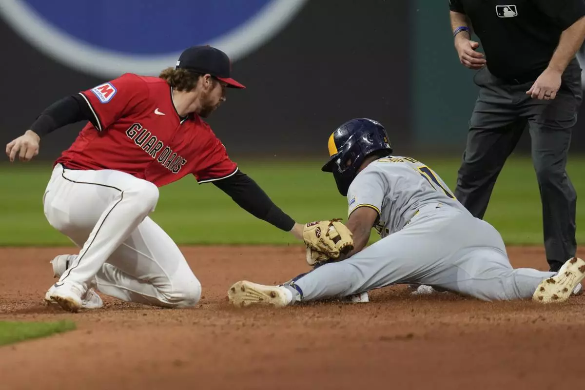 Milwaukee Brewers' Jackson Chourio, right, steals second base before the tag of Cleveland Guardians second baseman Daniel Schneemann, left, in the seventh inning of a baseball game in Cleveland, Monday, May 12, 2025. (AP Photo/Sue Ogrocki)