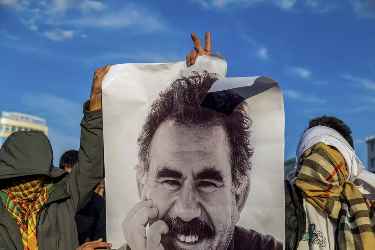 FILE - Youngsters hold a photograph of the jailed leader of the rebel Kurdistan Workers' Party, or PKK, Abdullah Ocalan as they gather to watch live on a tv screen a Pro-Kurdish Peoples' Equality and Democracy Party, or DEM, delegation members releasing an statement from Ocalan, in Diyarbakir, Turkey, Thursday, Feb. 27, 2025. (AP Photo/Metin Yoksu, File)