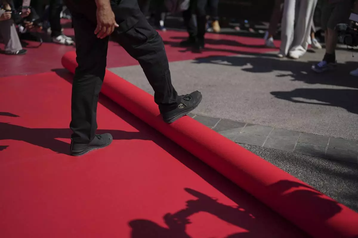 Crew members install the red carpet at the Palais des Festivals ahead of the opening ceremony of the 78th international film festival, Cannes, southern France, Tuesday, May 13, 2025. (AP Photo/Natacha Pisarenko)