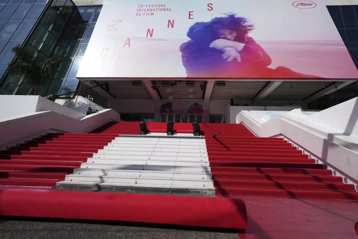 Crew members install the red carpet at the Palais des Festivals ahead of the opening ceremony of the 78th international film festival, Cannes, southern France, Tuesday, May 13, 2025. (AP Photo/Natacha Pisarenko)