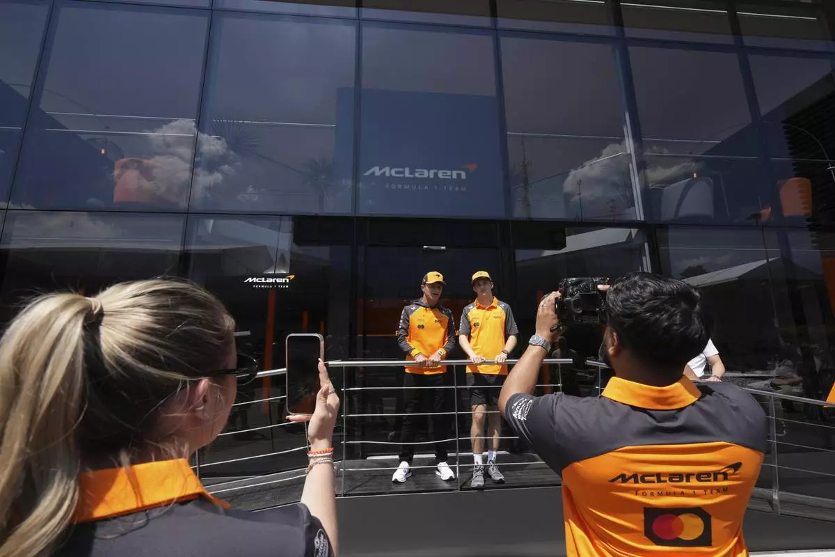McLaren driver Lando Norris of Britain, left, is flaked by his teammate Oscar Piastri of Australia in the paddock at the Dino and Enzo Ferrari racetrack, ahead the Italy's Emilia Romagna Formula One Grand Prix in Imola, Italy, Thursday, May 15, 2025. (AP Photo/Antonio Calanni)