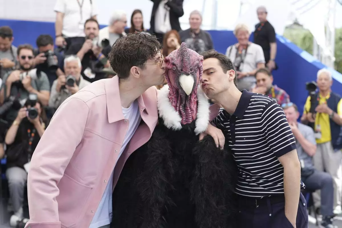 Director Raphael Quenard, left, a person in a bird costume and director Hugo David, right, pose for photographers at the photo call for the film 'I Love Peru' at the 78th international film festival, Cannes, southern France, Sunday, May 18, 2025. (AP Photo/Natacha Pisarenko)