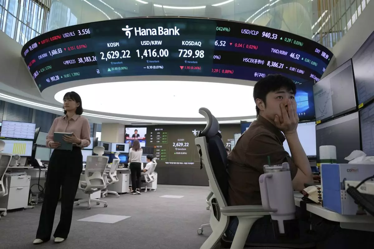 A currency trader watches monitors near a screen showing the Korea Composite Stock Price Index (KOSPI), top center left, and the foreign exchange rate between U.S. dollar and South Korean won, top center, at the foreign exchange dealing room of the KEB Hana Bank headquarters in Seoul, South Korea, Wednesday, May 14, 2025. (AP Photo/Ahn Young-joon)