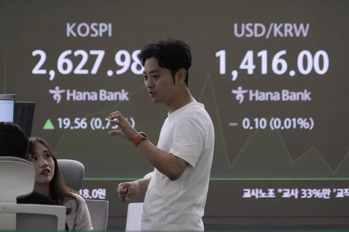 Currency traders work near a screen showing the Korea Composite Stock Price Index (KOSPI), left, and the foreign exchange rate between U.S. dollar and South Korean won at the foreign exchange dealing room of the KEB Hana Bank headquarters in Seoul, South Korea, Wednesday, May 14, 2025. (AP Photo/Ahn Young-joon)