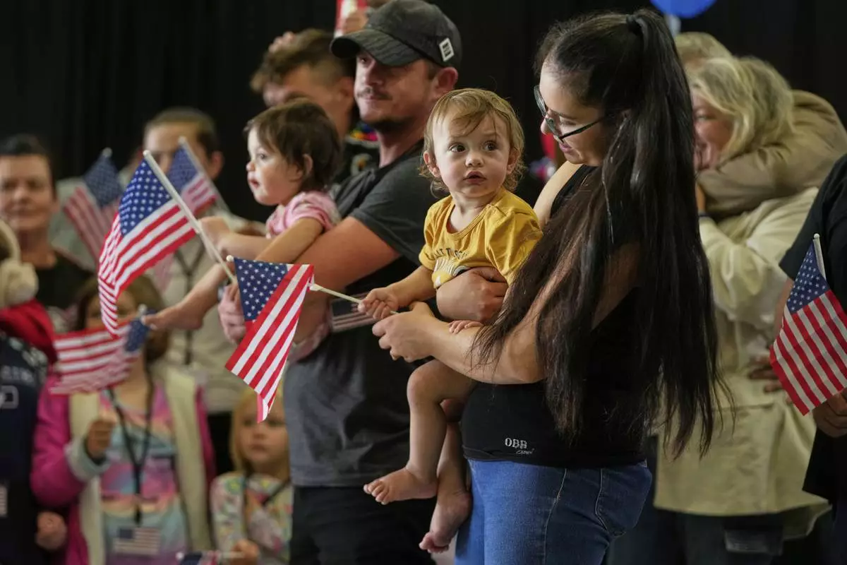 Afrikaner refugees from South Africa holding American flags arrive, Monday, May 12, 2025, at Dulles International Airport in Dulles, Va. (AP Photo/Julia Demaree Nikhinson)