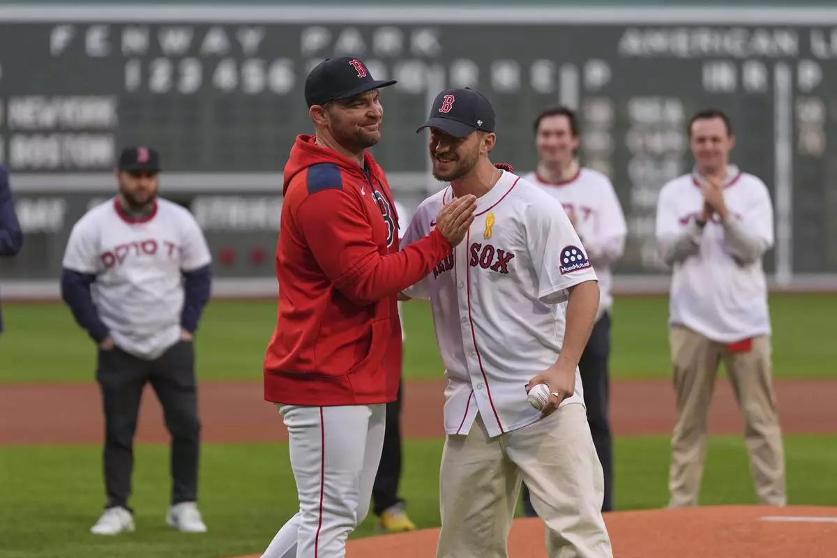 Omer Shem Tov, front right, a former Israeli hostage who survived over 500 days in Hamas captivity, gets a pat on the chest by Boston Red Sox pitcher Liam Hendriks, front left, after delivering a ceremonial first pitch prior to a baseball game between the Red Sox and the New York Mets at Fenway Park, Monday, May 19, 2025, in Boston. (AP Photo/Charles Krupa)