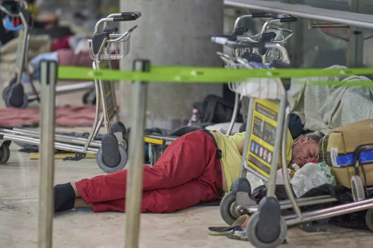 A person sleeps on the floor of Terminal 4 at Adolfo Suarez-Madrid Barajas Airport in Madrid, Spain, Thursday, May 15, 2025. (AP Photo/Manu Fernandez)