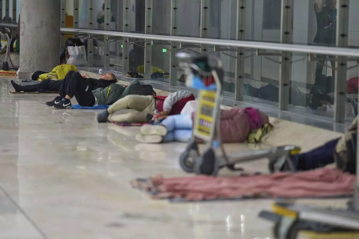 People sleep on the floor of Terminal 4 at Adolfo Suarez-Madrid Barajas Airport in Madrid, Spain, Thursday, May 15, 2025. (AP Photo/Manu Fernandez)