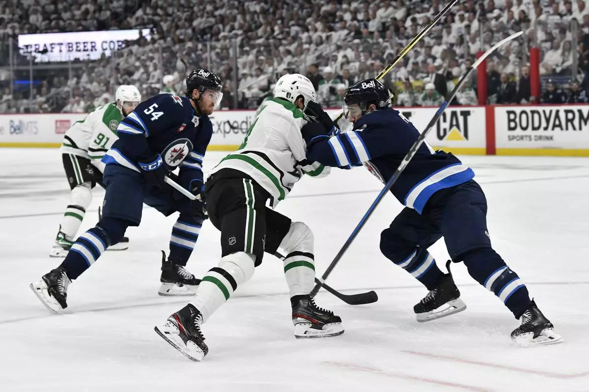 Winnipeg Jets' Neal Pionk (right) checks Dallas Stars' Jamie Benn (14) during first period NHL playoff hockey action in Winnipeg, Thursday, May 15, 2025. (Fred Greenslade/The Canadian Press via AP)