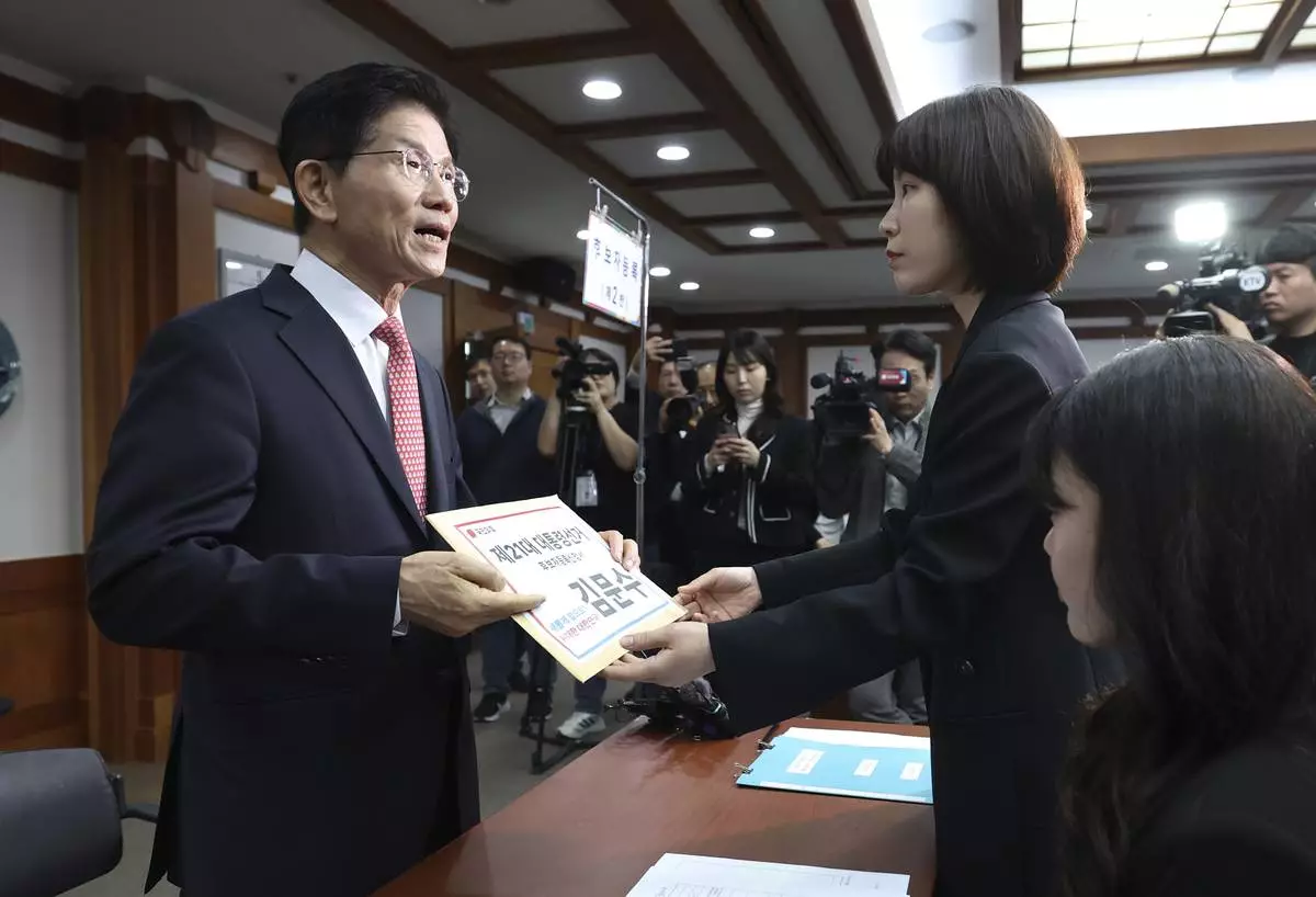 South Korea's People Power Party's presidential election candidate Kim Moon Soo, left, submits documents to register as a candidate to run in the June 3 presidential election, at the National Election Commission, Gwacheon, South Korea, Sunday, May 11, 2025. The letter read "The 21st Presidential election candidate registration application, Kim Moon Soo." (Yonhap via AP)