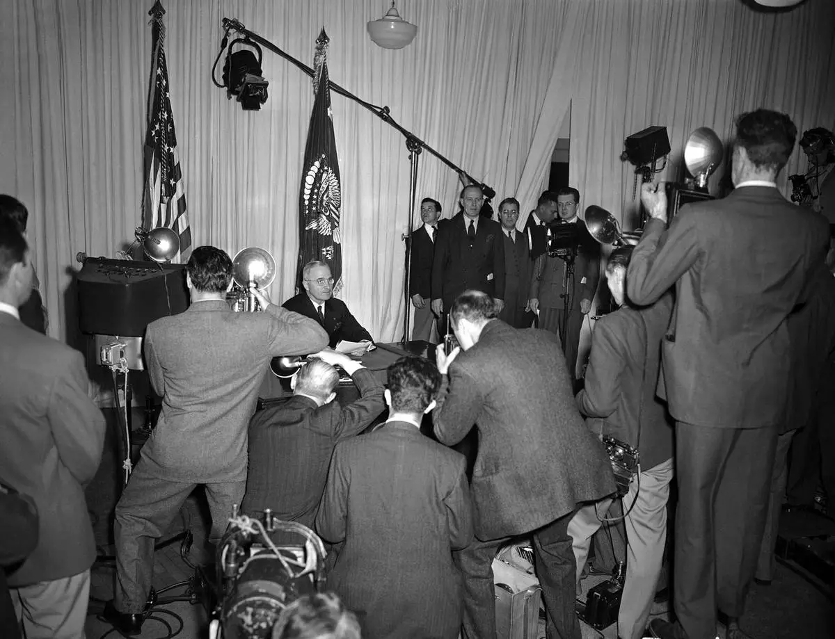 FILE - President Harry S. Truman sits at the close of his radio announcement from the White House in Washington, May 8, 1945 as cameramen record the historic occasion of the announcement of complete victory over the Germans. (AP Photo/Herbert K. White, File)