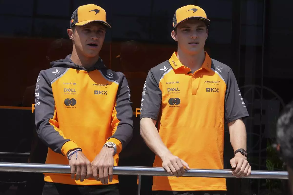McLaren driver Lando Norris of Britain, left, is flaked by his teammate Oscar Piastri of Australia in the paddock at the Dino and Enzo Ferrari racetrack, ahead the Italy's Emilia Romagna Formula One Grand Prix in Imola, Italy, Thursday, May 15, 2025. (AP Photo/Antonio Calanni)