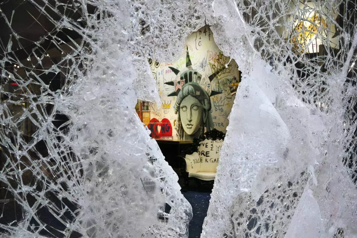 A Statue of Liberty painting is seen through a smashed Dolce and Gabbana store window in the SoHo neighborhood of New York on Monday, June 1, 2020. (AP Photo/Mark Lennihan, File)