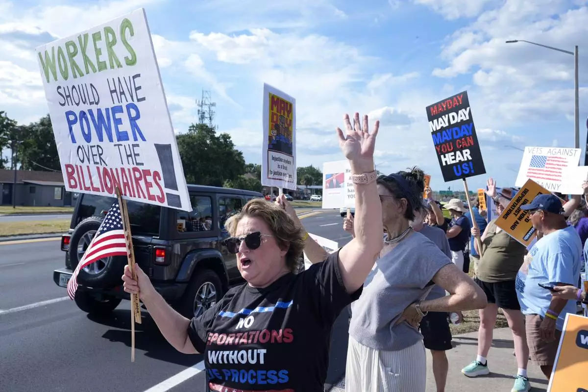 Demonstrators hold signs and wave to motorists in front of the Orange County Corrections Department during a May Day rally for worker and immigrant rights Thursday, May 1, 2025, in Orlando, Fla. (AP Photo/John Raoux)