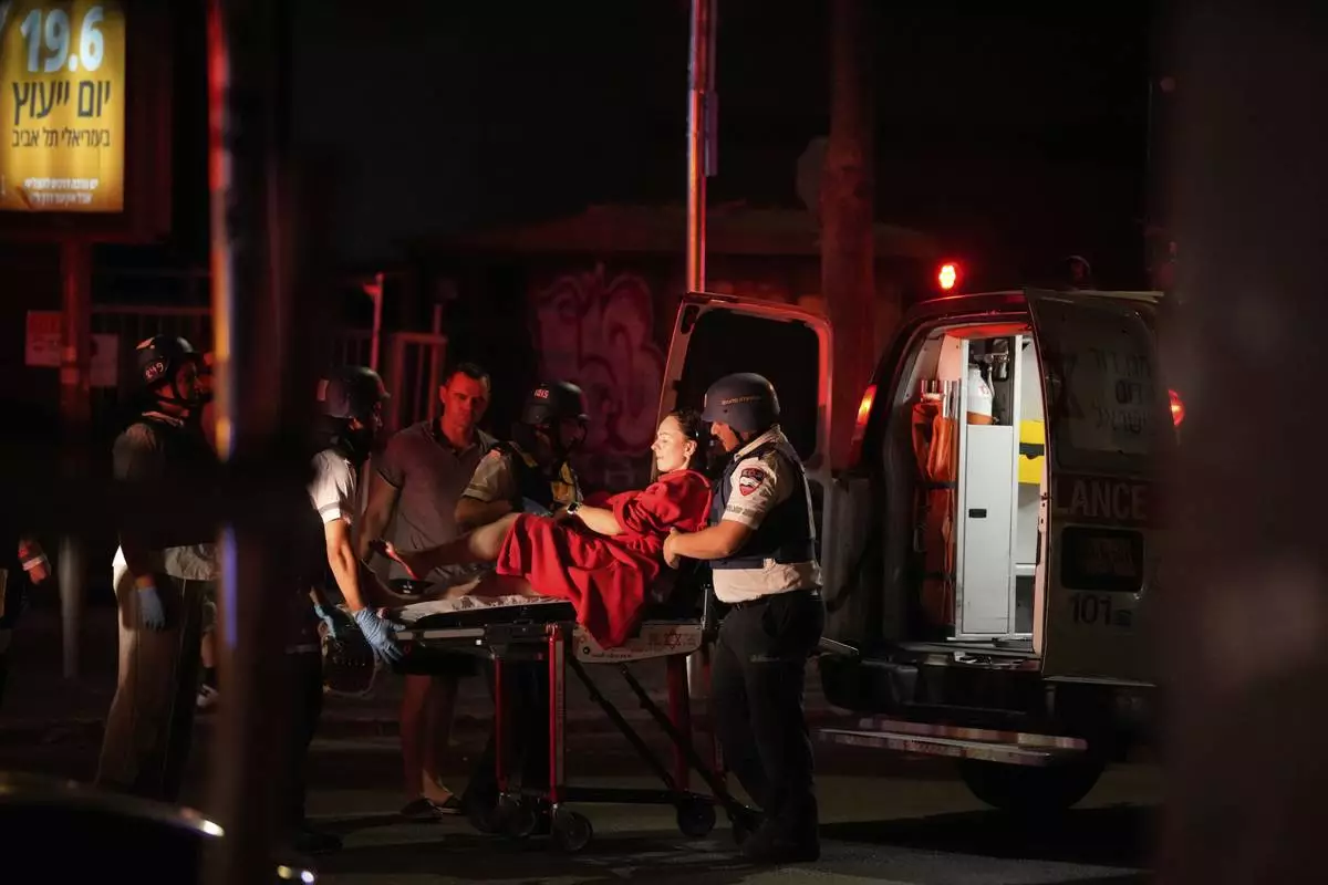 Paramedics evacuate a wounded woman from a building struck by a missile fired from Iran, in Tel Aviv, Israel, on Friday, June 13, 2025. (AP Photo/Tomer Appelbaum)