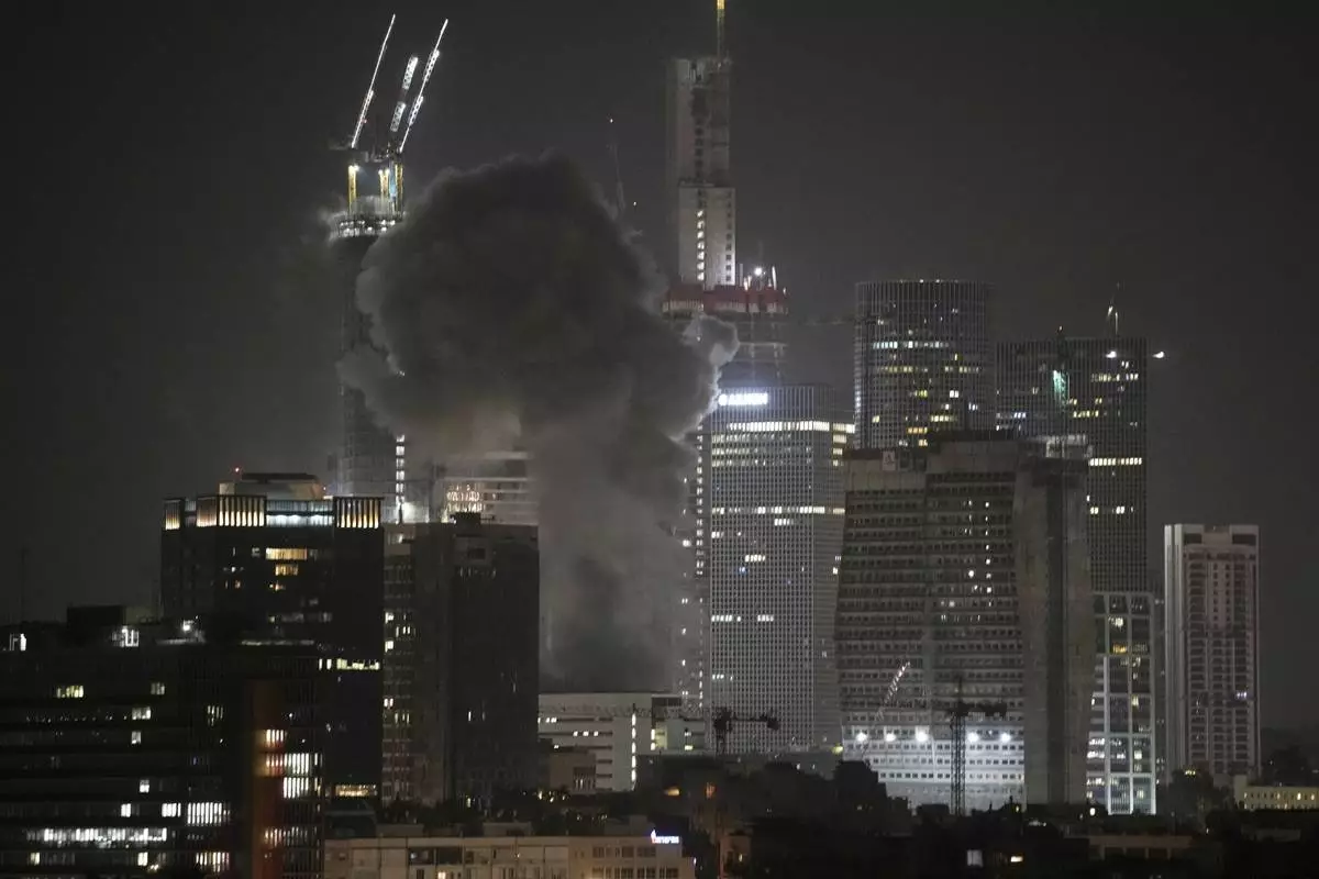 Smoke billows after a projectile hit a building in Tel Aviv, Israel, early Saturday, June 14, 2025. (AP Photo/Leo Correa)