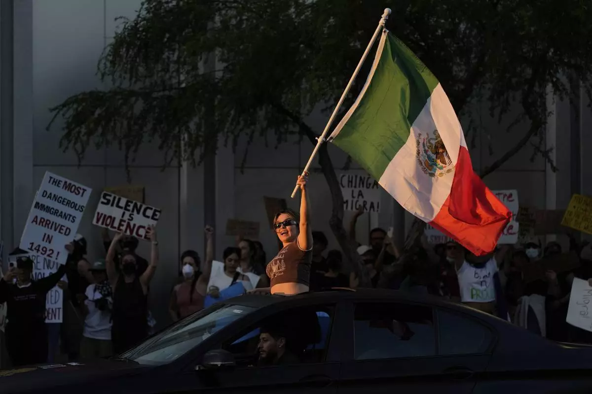 A woman waves a Mexican flag during protests over President Donald Trump's stepped-up enforcement of immigration laws, Wednesday, June 11, 2025, in Las Vegas. (AP Photo/John Locher)